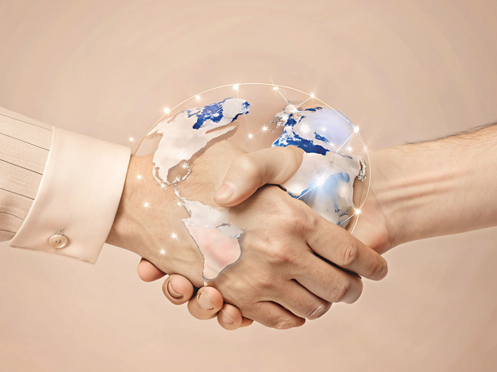 a close-up of two hands shaking, overlaid with a glowing globe showing continents and sparkling light effects, symbolizing global partnership