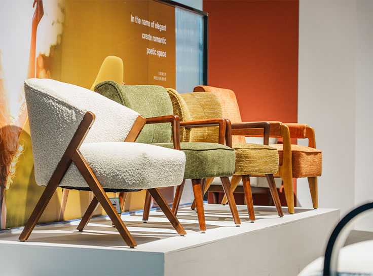a row of modern wooden armchairs with textured upholstery, displayed on a white platform in a stylish showroom